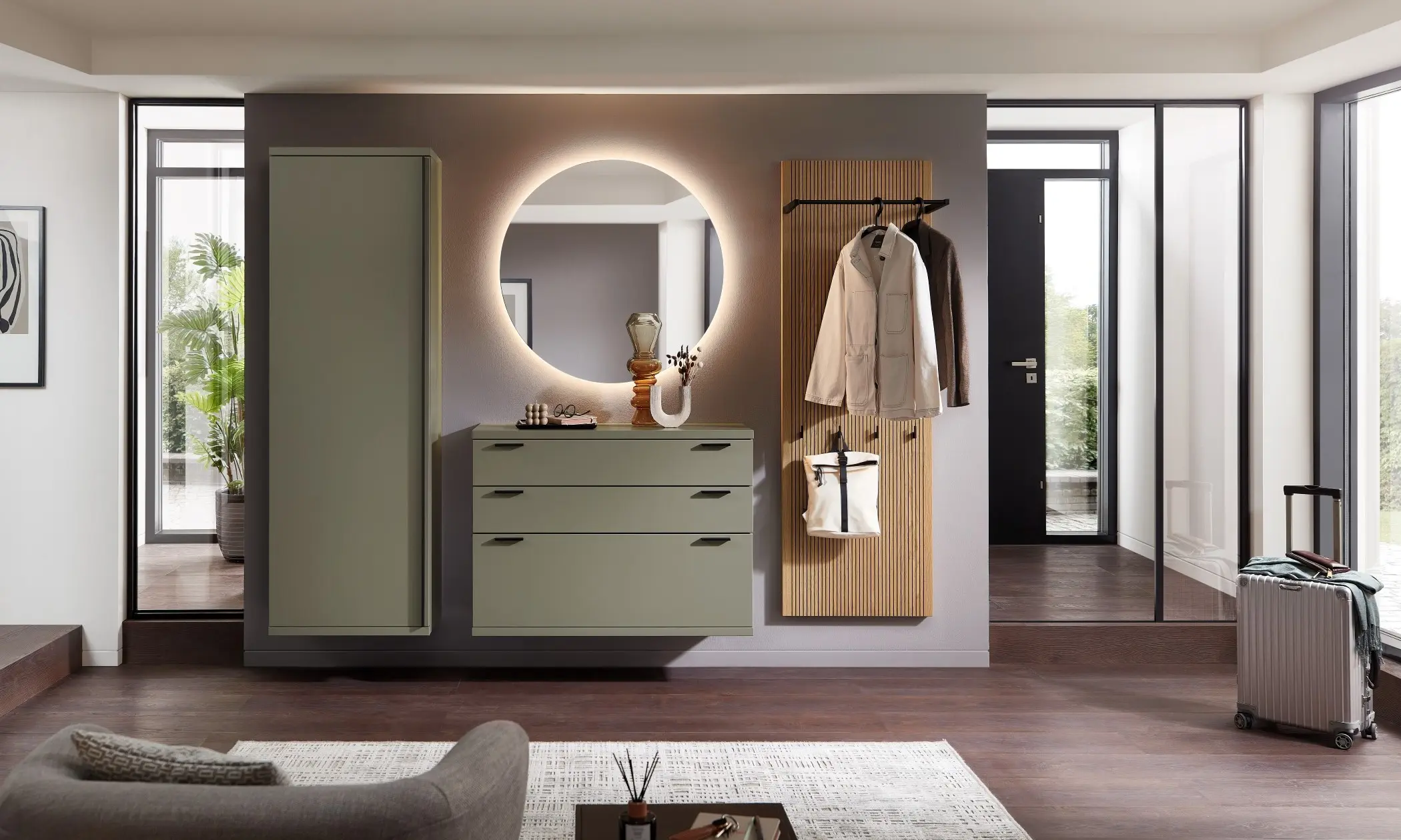 Sie sehen eine olivgrüne Garderobe mit Eichepaneelen abgesetzt, Spiegel beleuchtet und Stauraumelement für Jacken